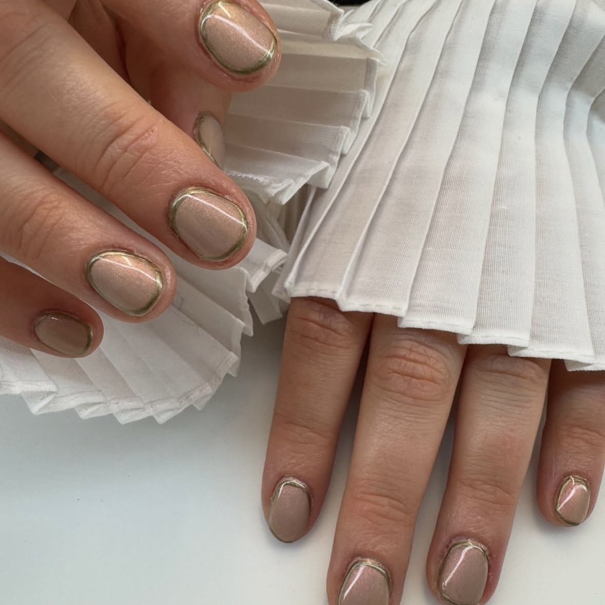 A shimmery nude manicure bordered with a metallic shade.