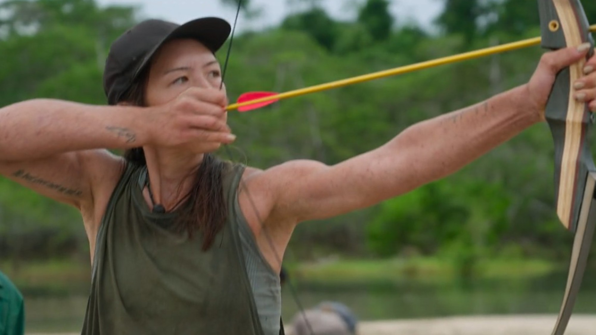 Abby Chu shooting an arrow in Outlast: The Jungle.
