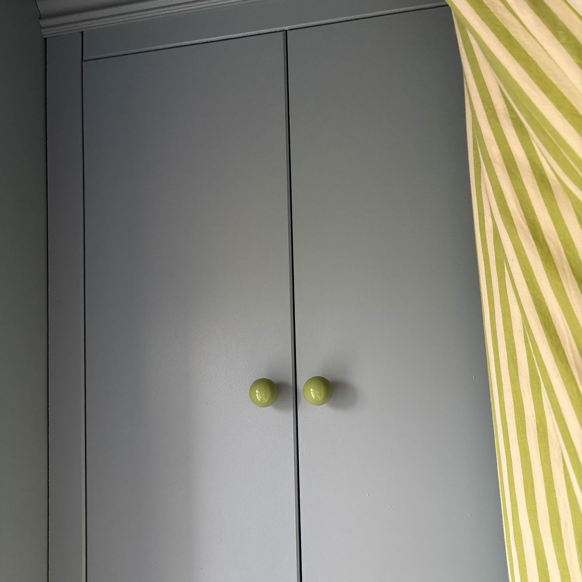 Pale blue/purple painted cabinetry with green knobs