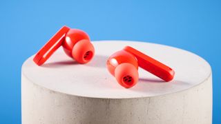 the nothing cmf buds pro 2 cmf by nothing buds pro 2 in bright orange shown in the smart dial charging case against a blue tom's guide background