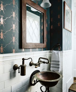 cloakroom with insect wallpaper and white tiles and brass taps