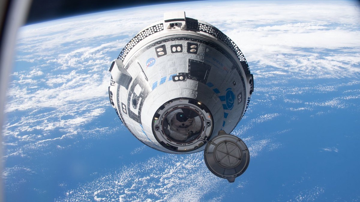 a grey-and-blue conical spacecraft floats above Earth with a hatch open on its small end