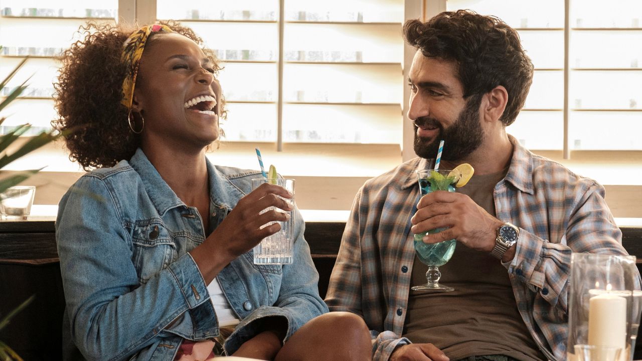 issa rae and kumail nanjiani sip cocktails in a booth laughing in a still from the lovebirds