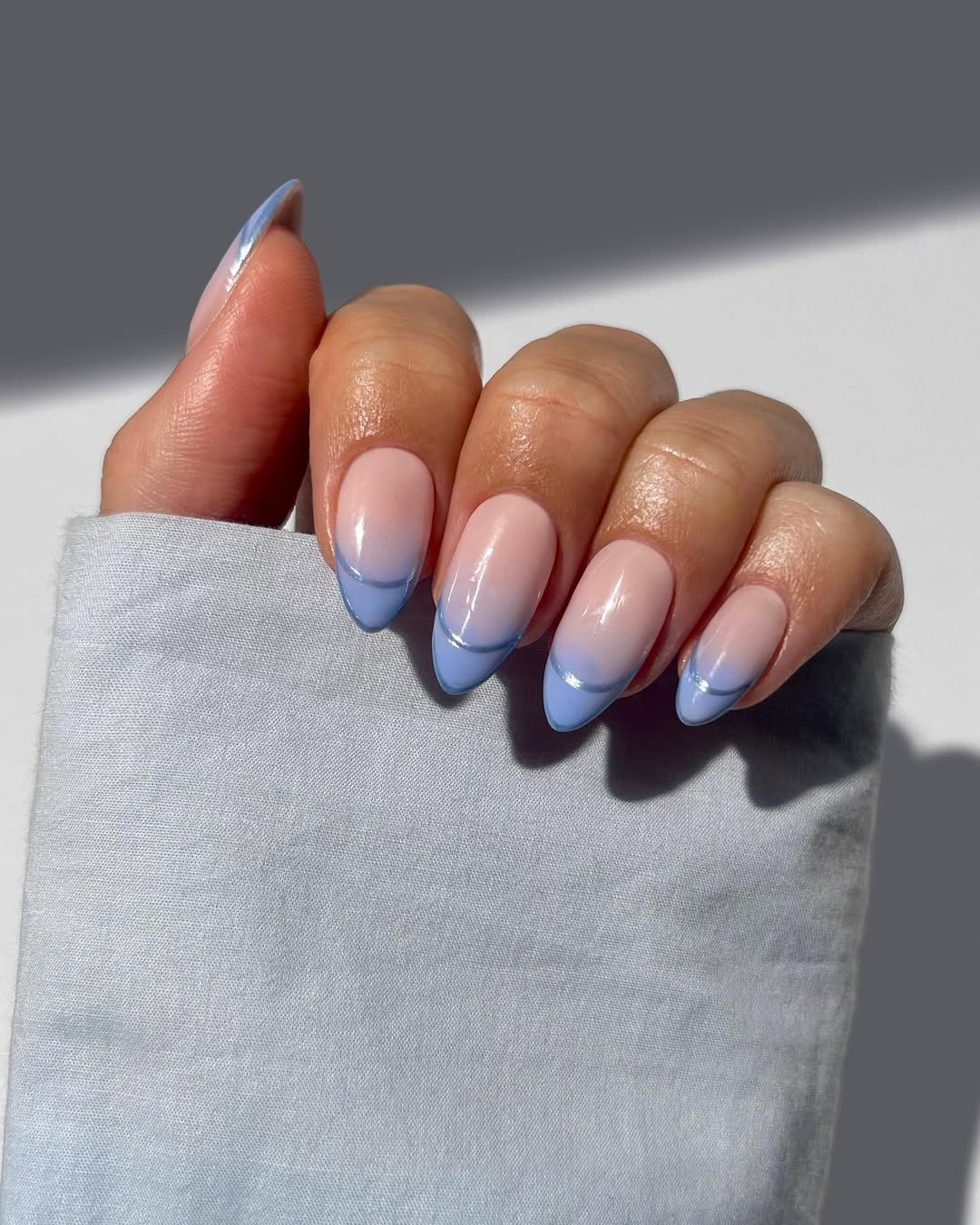 a person wearing a blue french manicure with a chrome outline