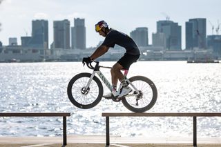 The Canyon Aeroad CFR Tokyo edition being ridden along a thin balustrade with a gap being bridged by the rider on the bike in front of water and tall buildings