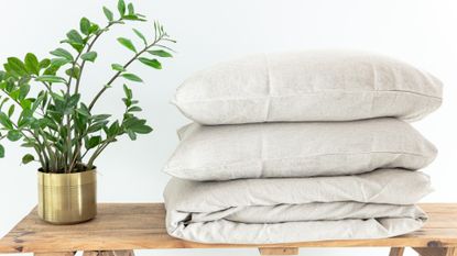 stack of bed linen on a table with a potted plant