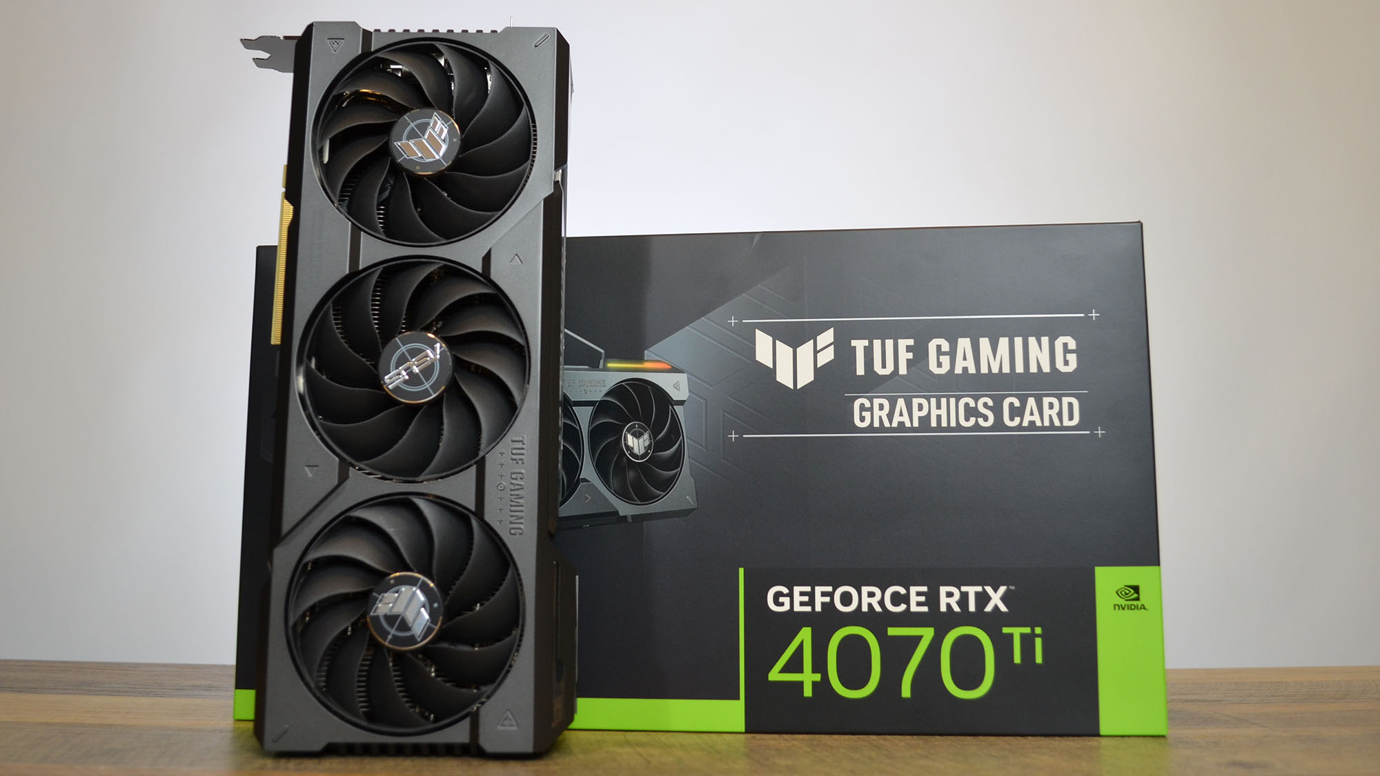 An Nvidia GeForce RTX 4070 Ti graphics card on a wooden table with its retail packaging
