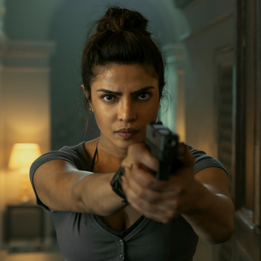 priyanka chopra points a gun down a hallway in the movie heads of state