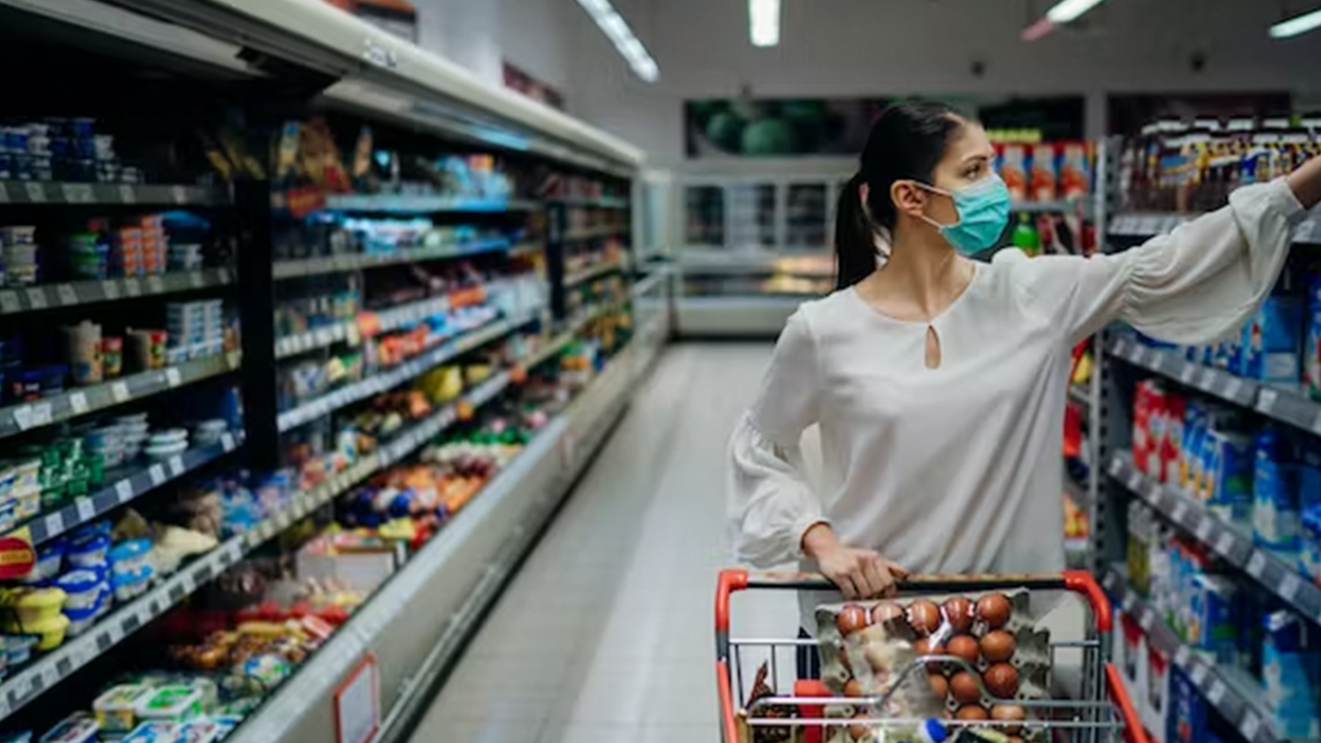 Woman in a blue face mask shops in a grocery store.