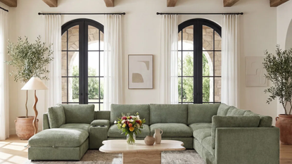a living room with tall ceilings and a large green sectional