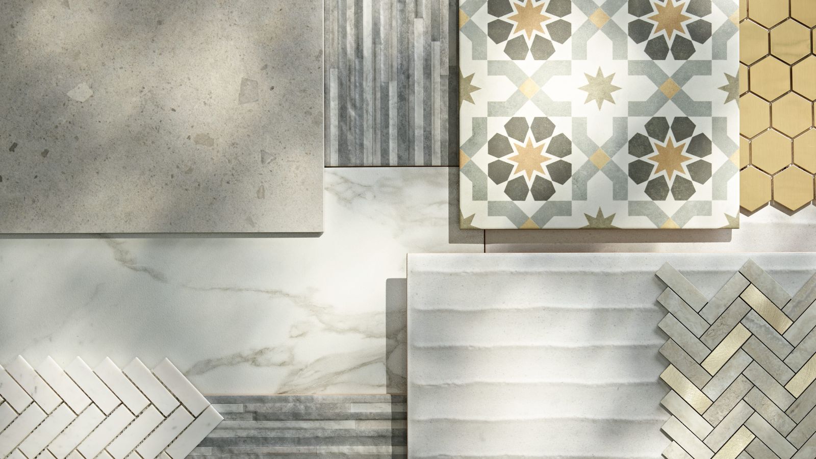 A flat-lay display of various tile samples showing a range of sizes and styles, including large-format terrazzo and marble slabs, geometric Moorish star patterned encaustic tiles, gold hexagonal mosaic, and small herringbone marble tiles in both white and metallic finishes.