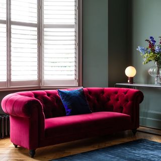 green living room with pin velvet sofa and flower vase