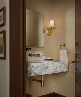 A neutral bathroom with a marble sink and gold hardware