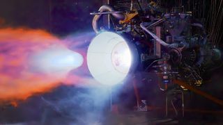 a rocket engine sits horizontally on a test stand outside, belching hot fire