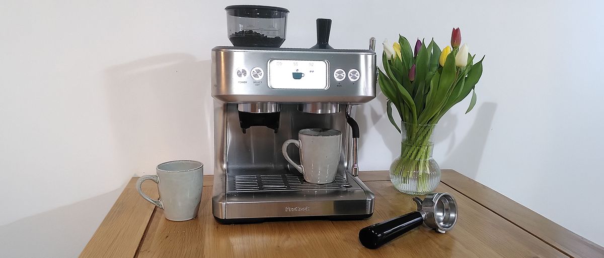 ProCook Barista Bean to Cup Espresso Coffee Machine on a table with two mugs and a vase of flowers