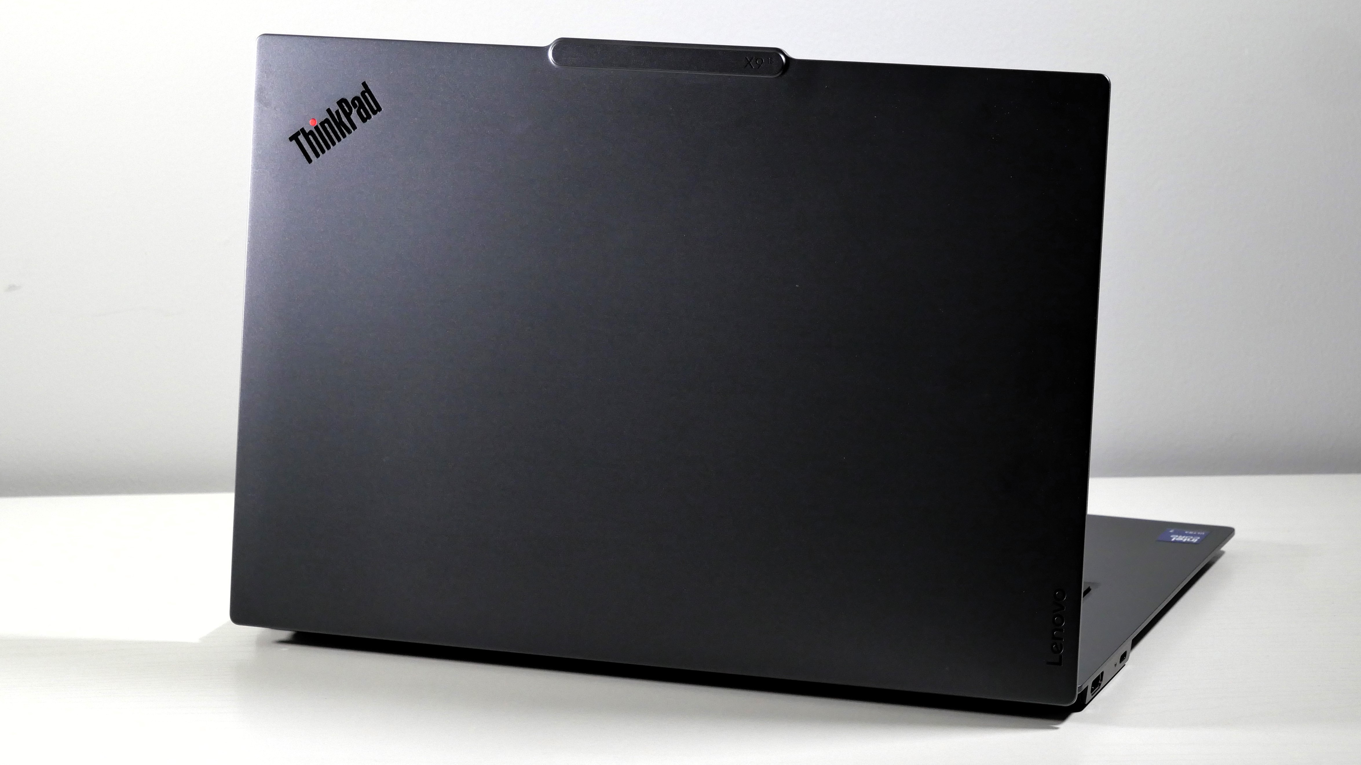 Lenovo ThinkPad X9-15 Gen 1 Aura Edition open on a white desk, highlighting the dark silver lid.