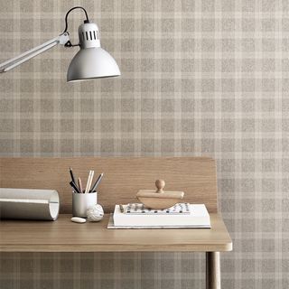 room with printed check wallpaper on wall and table with white table lamp