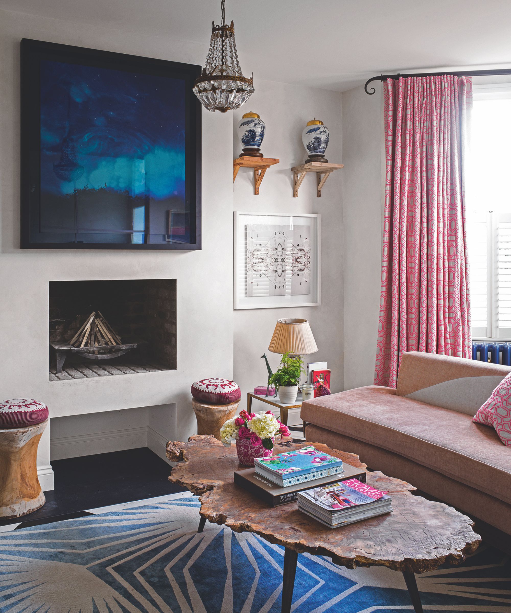 Living room with antique vases, organic wood coffee table, velvet sofa, blue rug, chandelier and abstract painting