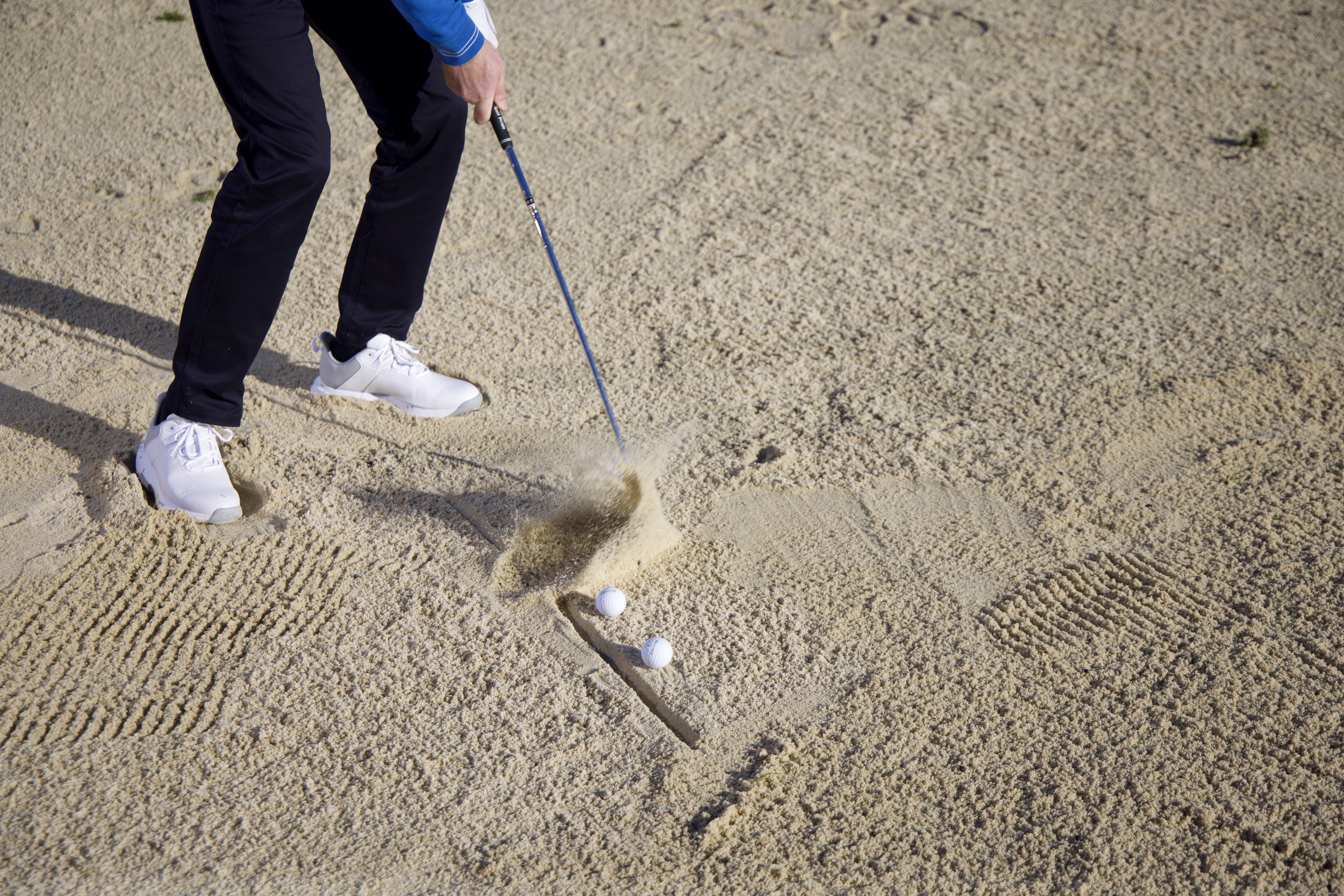 Keith Wood hitting the first of three balls in a line out of the sand in a bunker