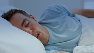 A person asleep in bed with their mouth slightly open