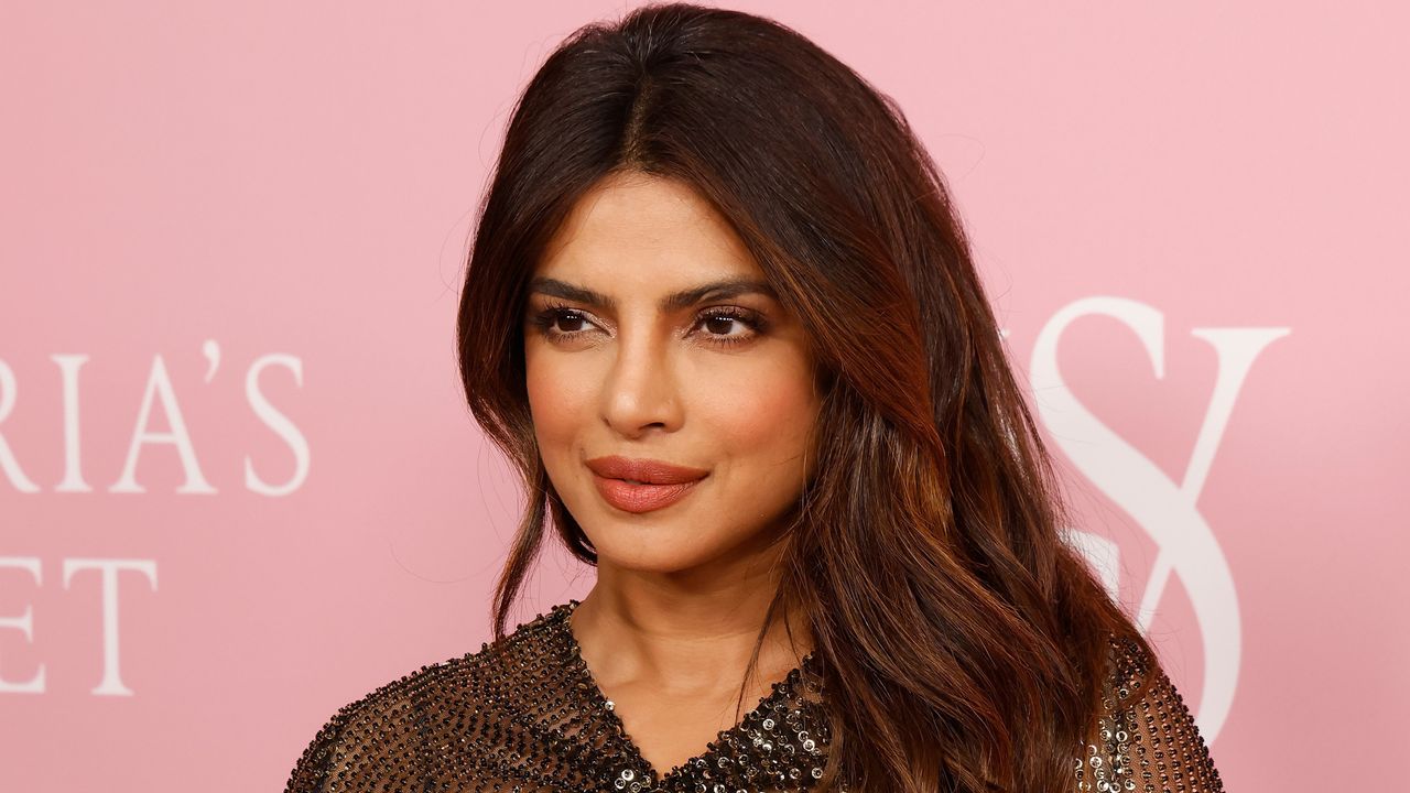 Priyanka Chopra Jonas on red carpet in black dress with pink background