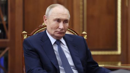 Russia's President Vladimir Putin sits on gilded chair in a suit