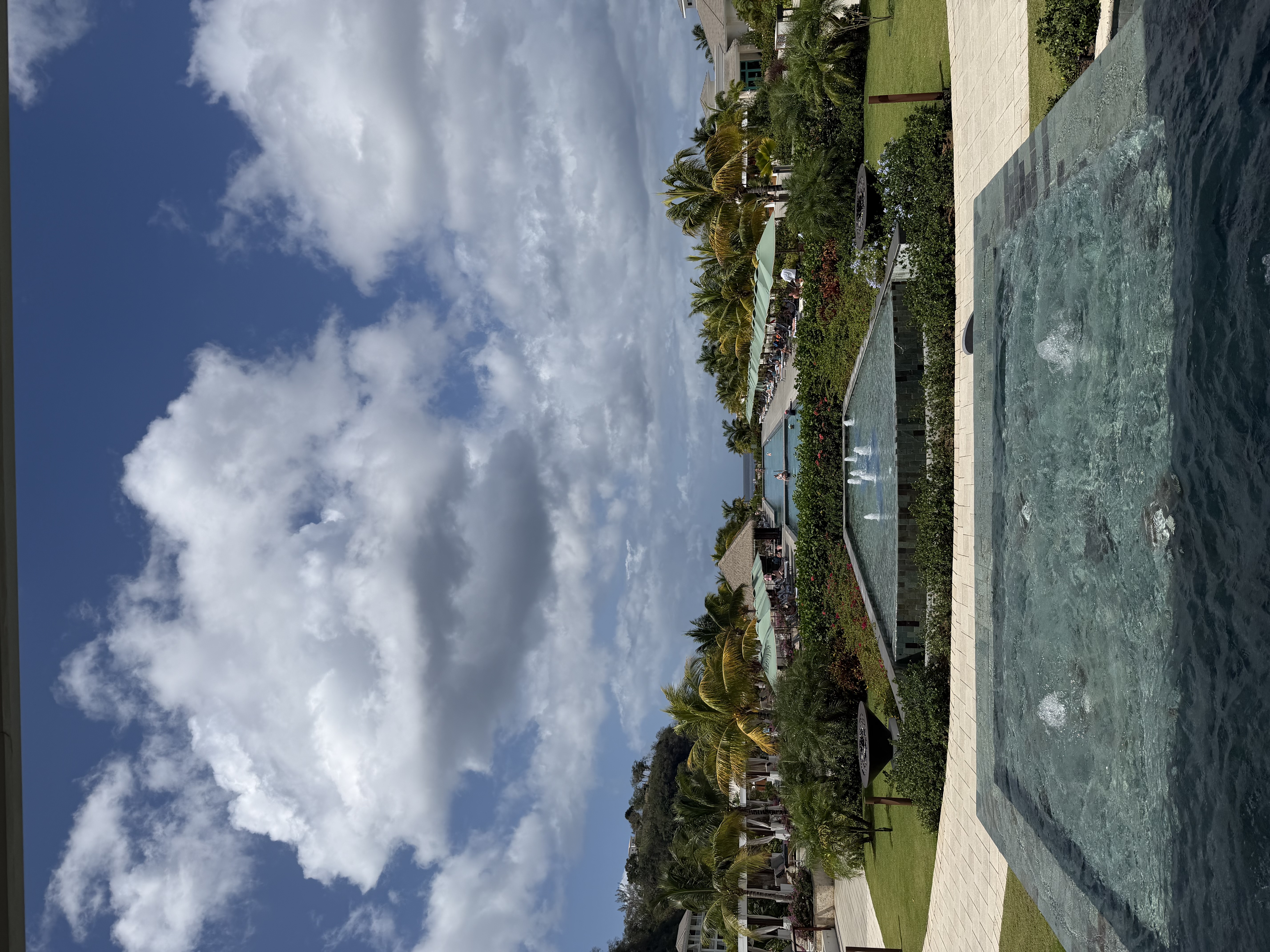 a tropical island with pools and clouds in the sky