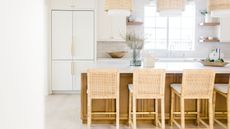 white and wood kitchen with rattan pendants and bar stools, large kitchen island, white countertops, open shelving, tiled wall