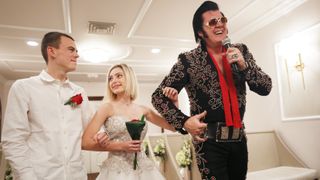 An Elvis impersonator walks a couple down the aisle of a Las Vegas wedding ceremony