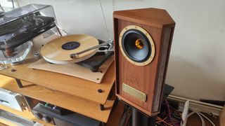 The Tannoy Autograph Mini pictured in a room next to a wooden sideboard and a record player