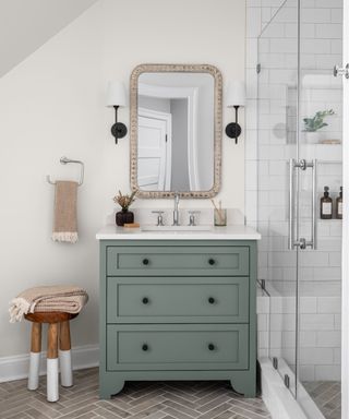 bathroom with white walls, white shower tiles, gray-green vanity and gray tiled flooring