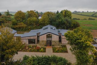 A modern barn conversion with manicured gravel drive and landscaped gardens 