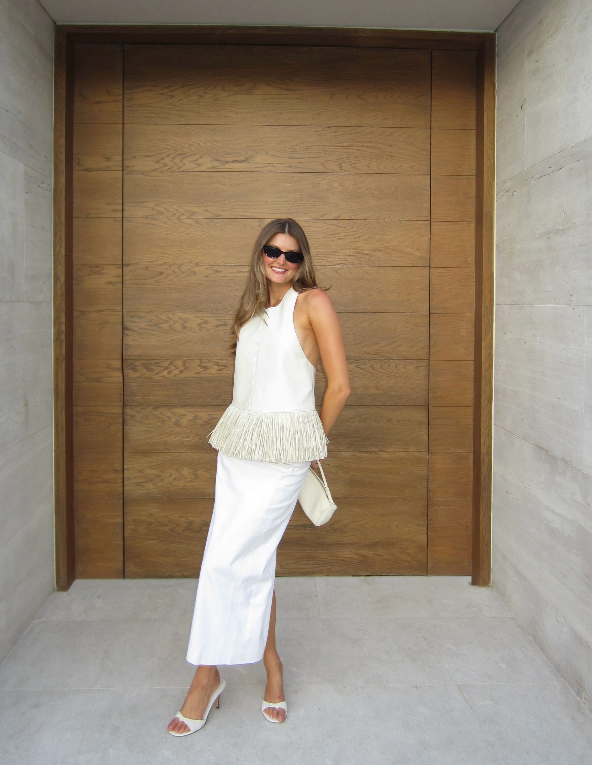 Sara wears a fringe top with a white midi skirt.