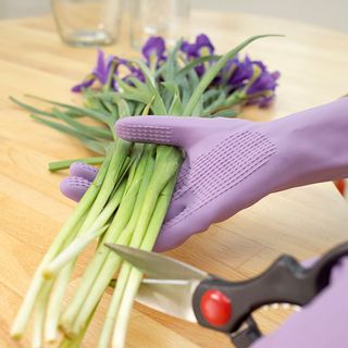 purple rubber gloves green vegetables and scissors on wooden table