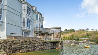 White, four story riverfront property looking over Fowey River.