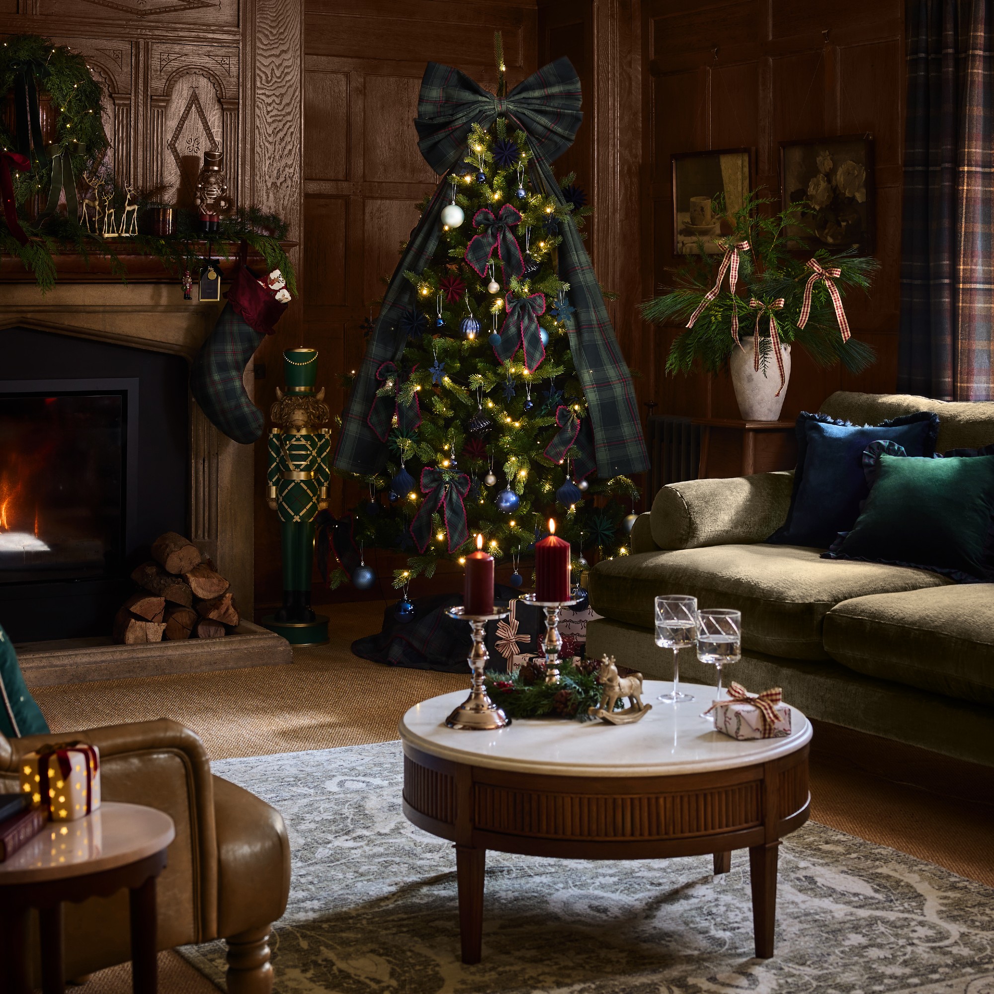 A wood-panelled living room with a Christmas tree in the corner decorated with tartan bows