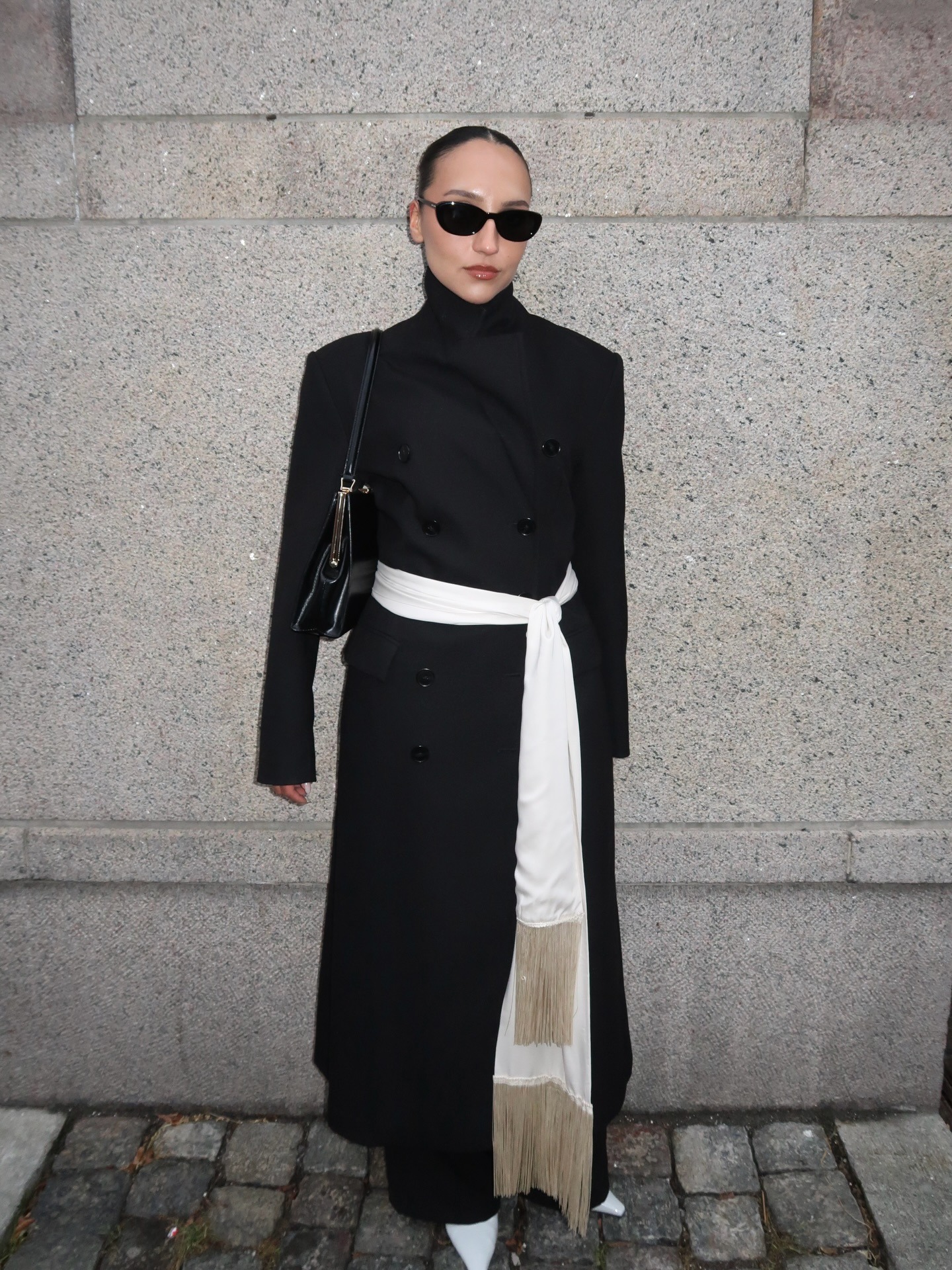 Woman in black coat and fringe tassel scarf