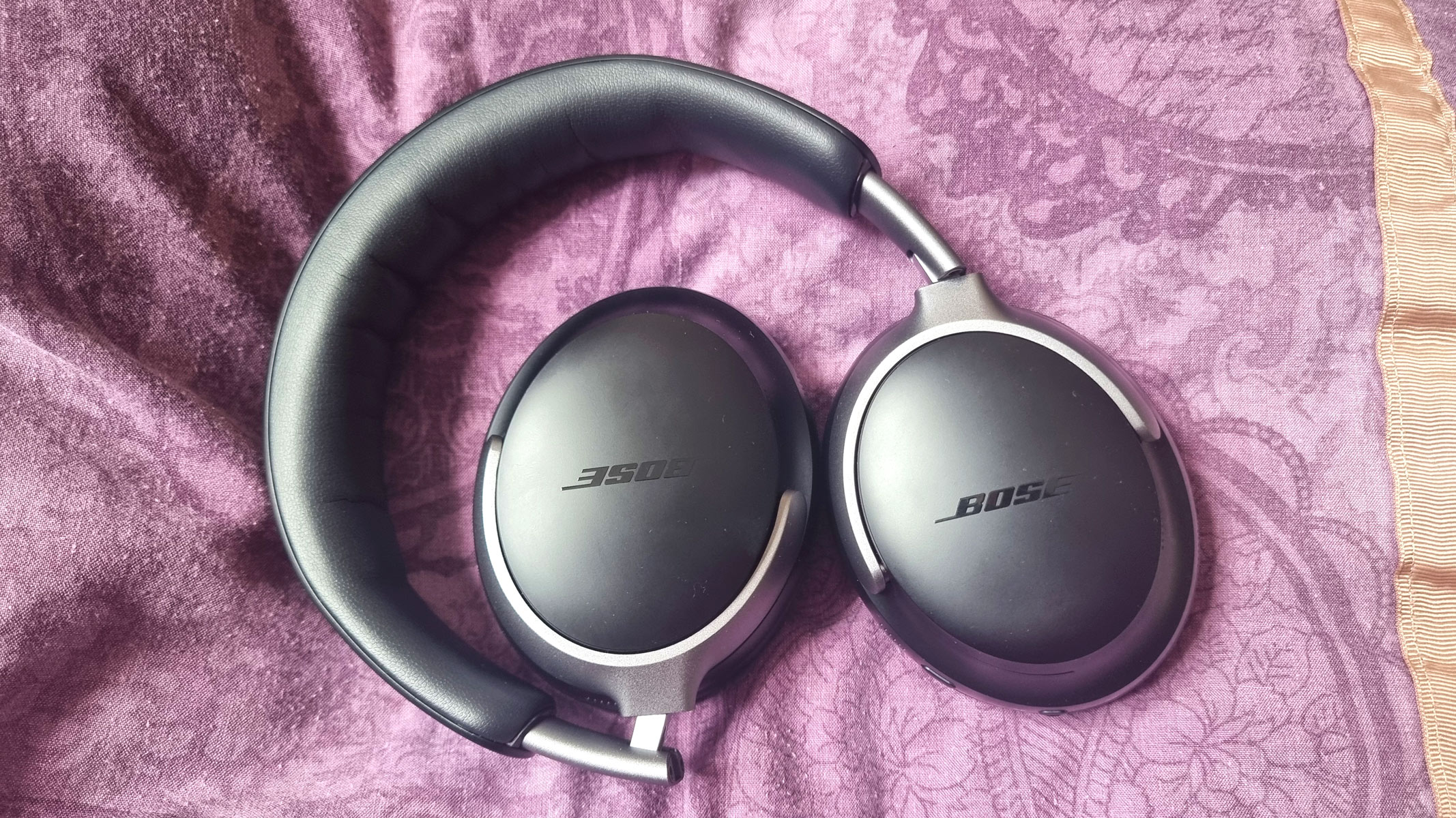 Bose QuietComfort Headphones laid out on a purple pillow