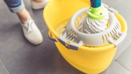 Cleaning with a mop in yellow bucket