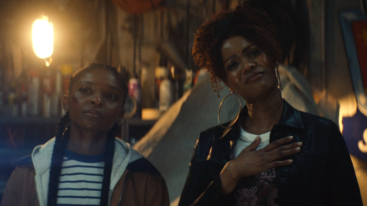 Riri Williams (Dominique Thorne) and Ronnie Williams (Anji White) watch a digital recording on Ironheart