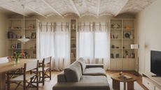 A spacious living room with white open shelving cabinets, a dining space and a sofa set with a coffee table and a TV