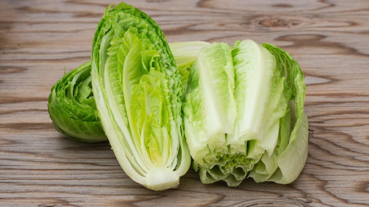 Fresh romaine lettuce sliced in half on a wooden background