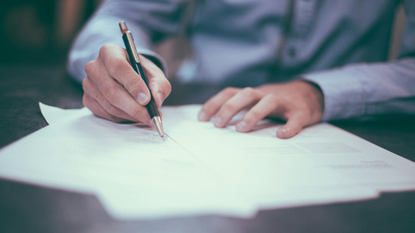Image of white male hands holding a pen and writing