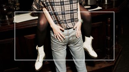 Girl sitting on a bar counter with a boy standing between her legs, holding her hands in the boys bottom