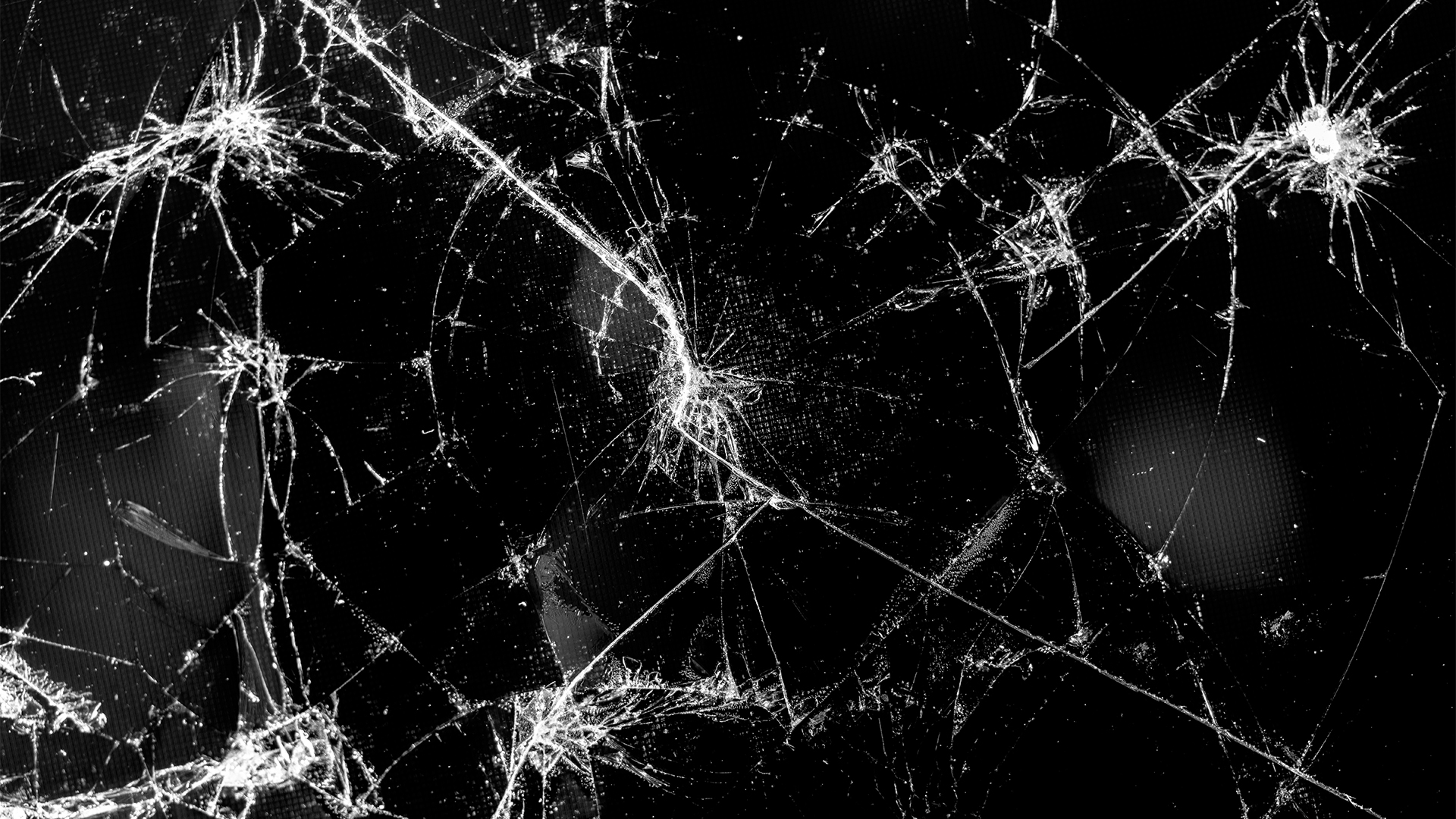 Cracked and shatter pane of glass fracturing against a black backdrop. 
