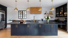 blue and marble kitchen with marble wall, blue cabinetry, hardwood floor, copper pendant lights, black countertop, open shelving, glazed wall units, 