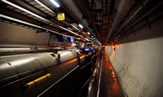 A long, circular concrete tunnel filled with scientific equipment