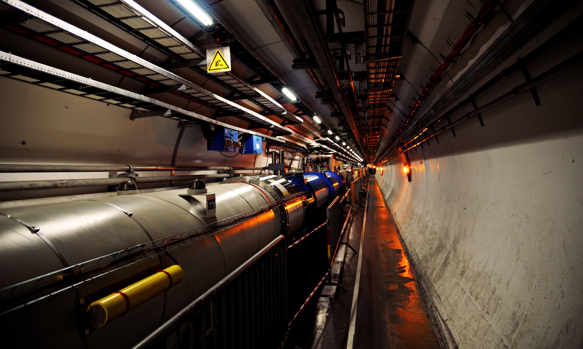 A long, circular concrete tunnel filled with scientific equipment