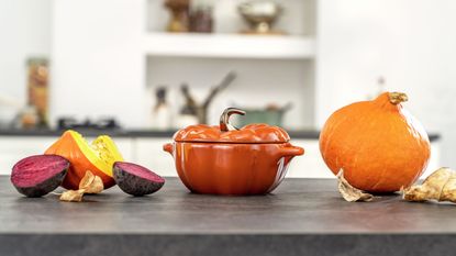 Pumpkin casserole dish from Staub on table with a real pumpkin and vegetables 