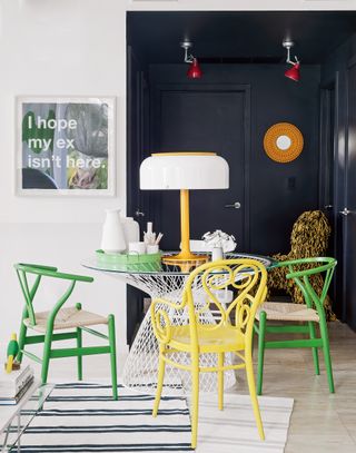 Black and white dining room with green and yellow chairs